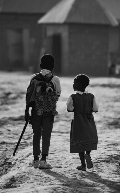 Two children walking to school at first light